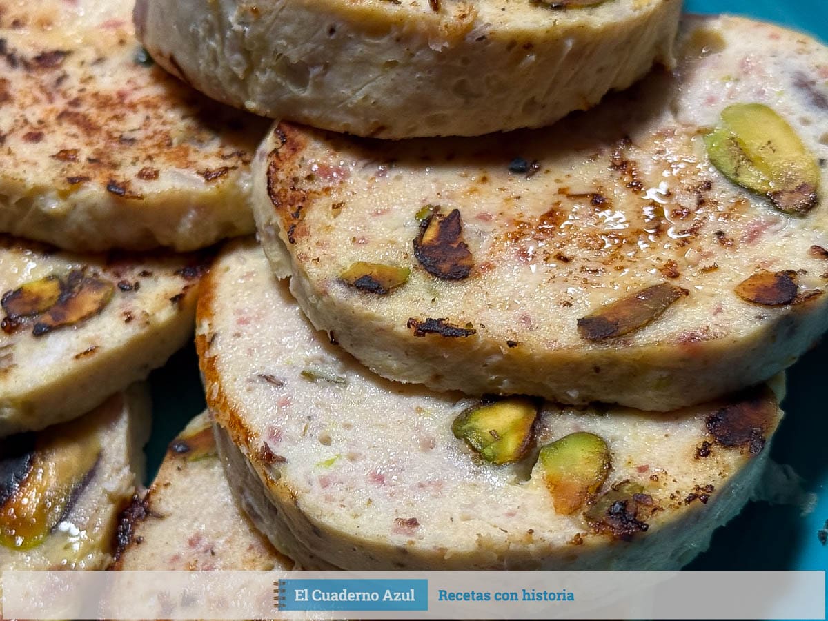 fiambre de pollo con pistachos cortado en medallones sobre plato azul