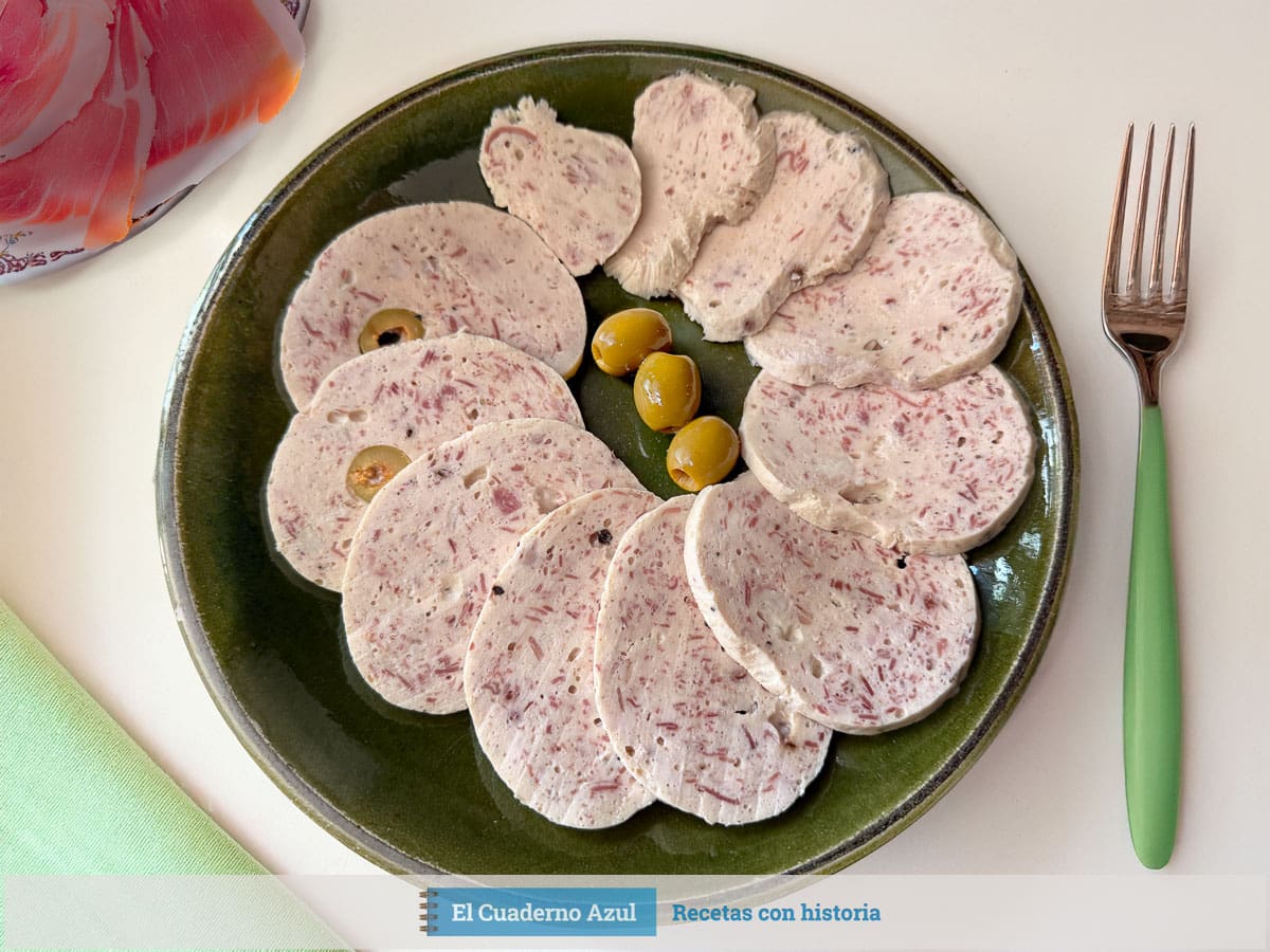 Fiambre de pollo y jamón casero cortado en lonchas finas con aceitunas verdes sobre plato verde